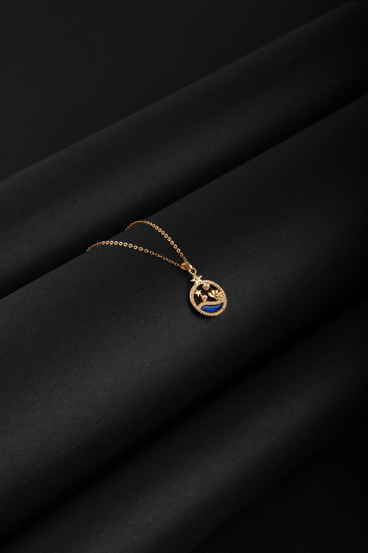Gold necklace with a blue pendant on a black fabric background