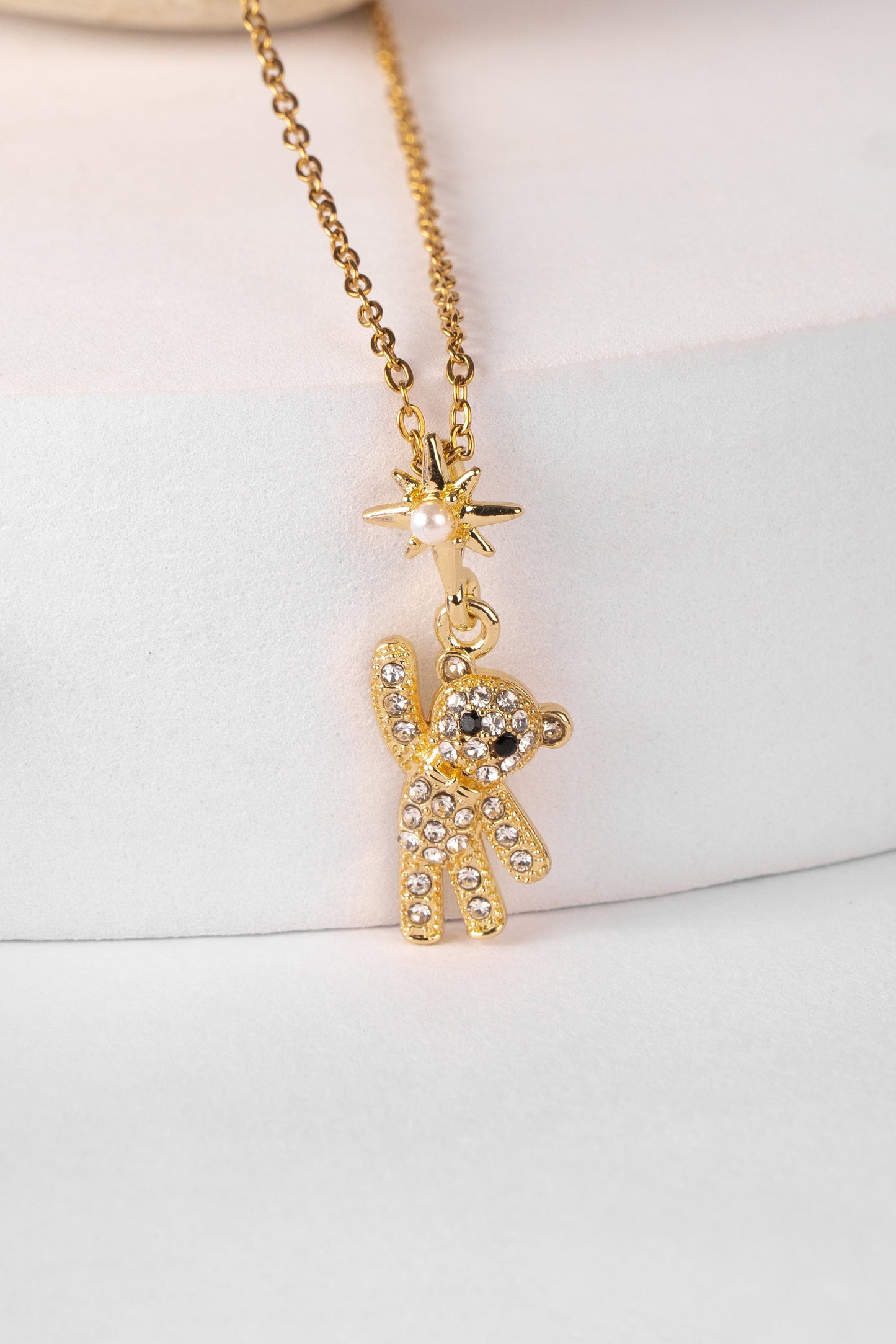 Gold teddy bear pendant necklace on a white background
