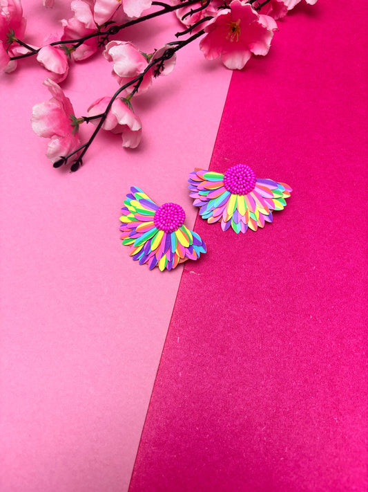 Colorful flower-shaped earrings on a pink background with cherry blossoms.