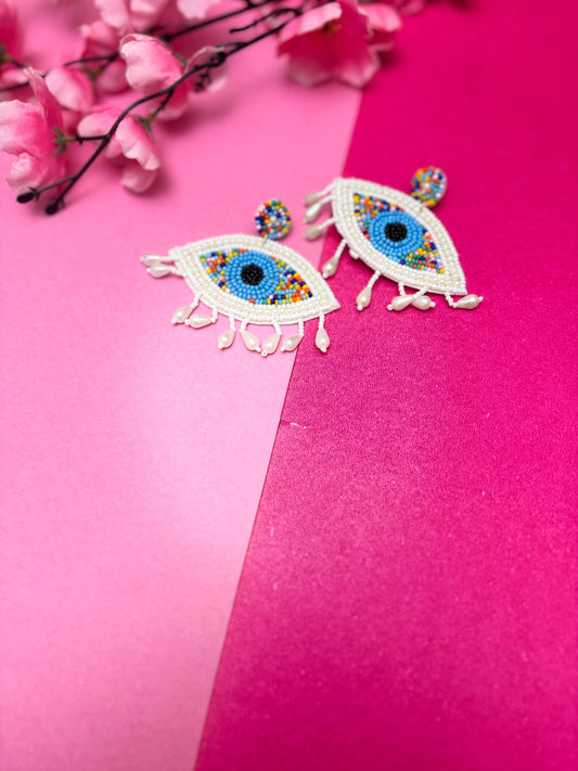 Colorful eye-shaped earrings on a pink background