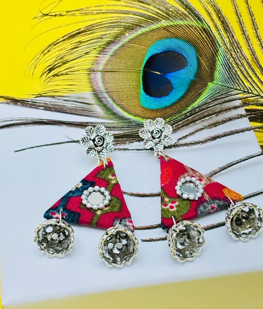 Colorful triangle-shaped earrings with floral patterns on a peacock feather background