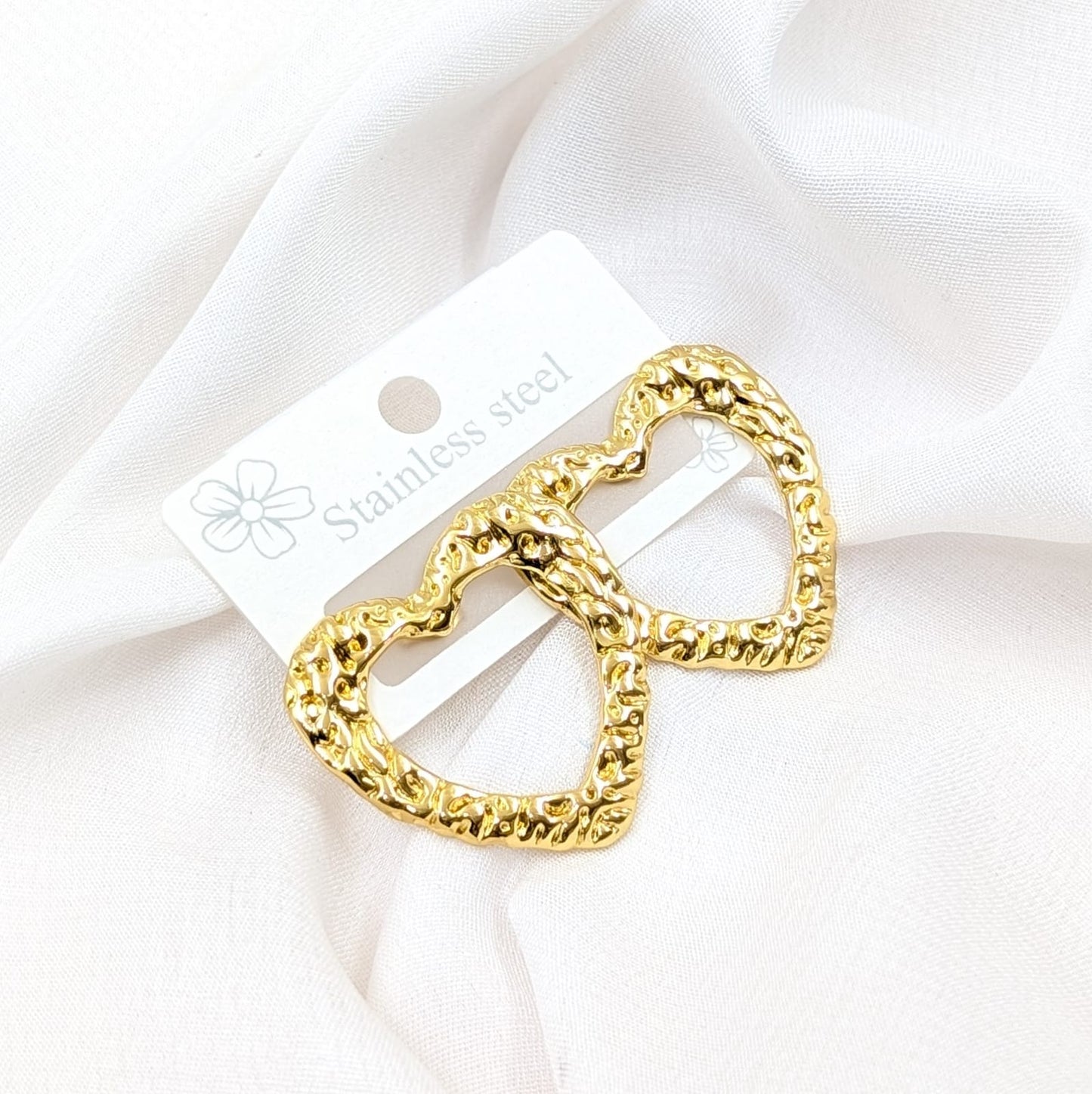 Gold chain belt buckle on a white card with 'Stainless Steel' text, against a white fabric background.