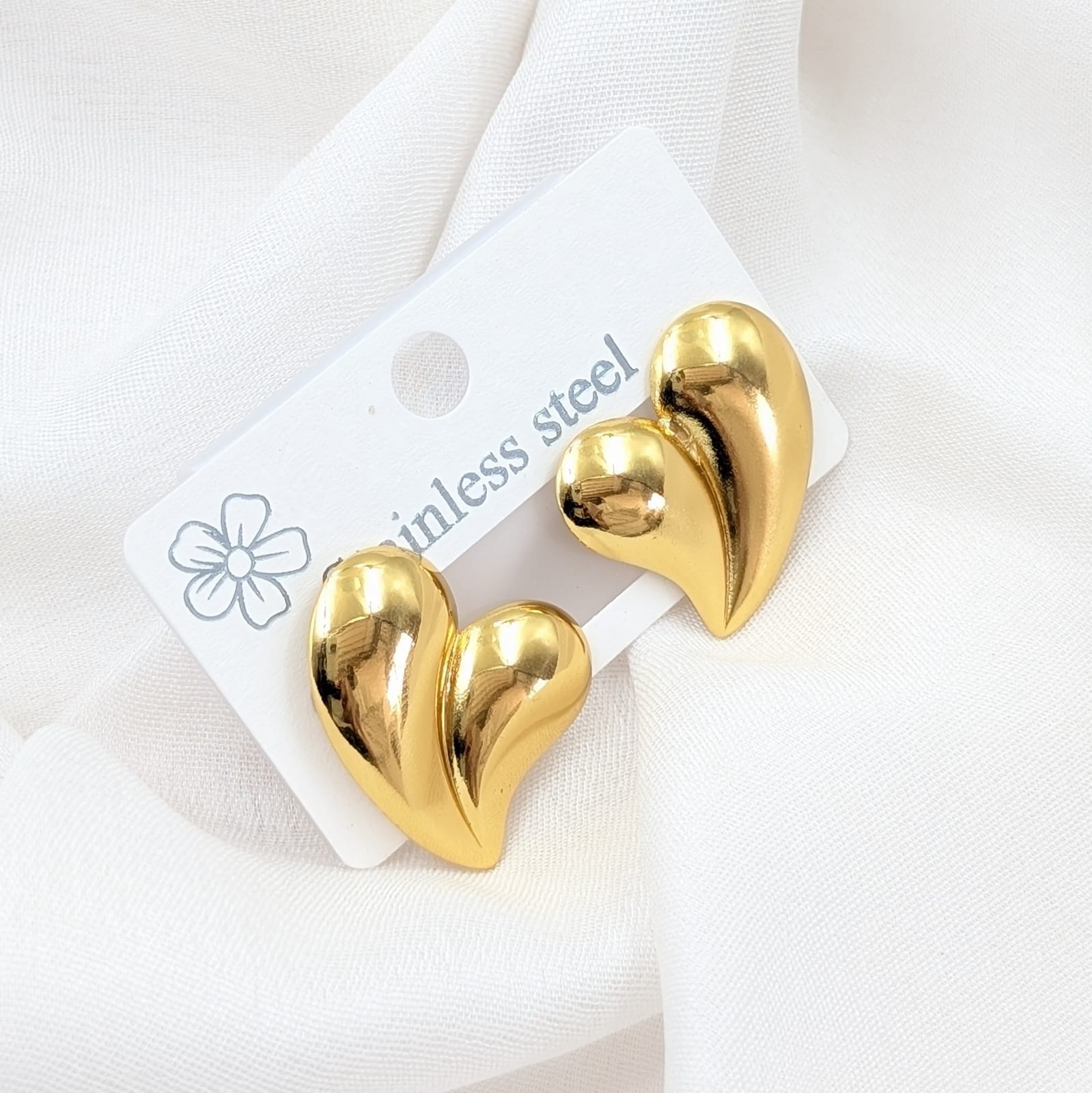 Gold heart-shaped earrings on a white card with 'ainless steel' text.
